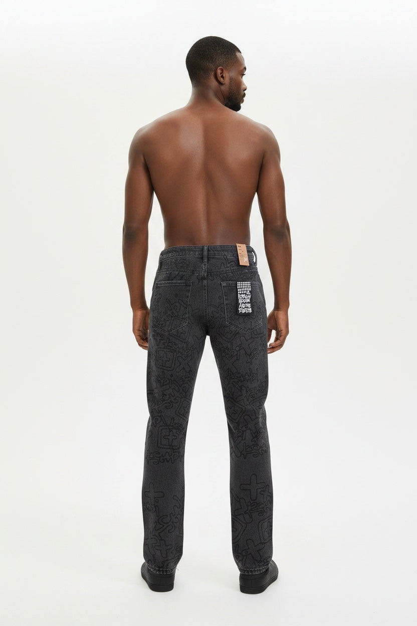 A shirtless man viewed from the back wearing dark gray patterned jeans with a visible &